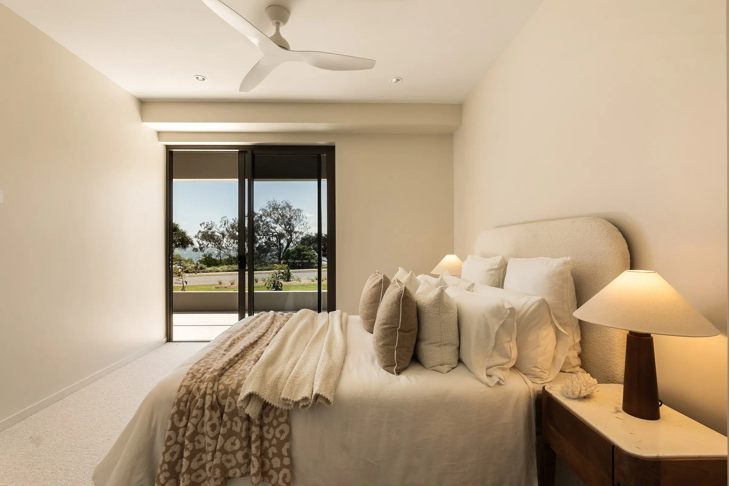 Main bedroom with a bedside lamp and sliding doors to the balcony